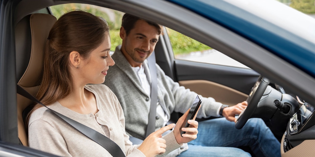 Casal em um carro, vendo o celular, representando a tecnologia do OnixPlus no carro